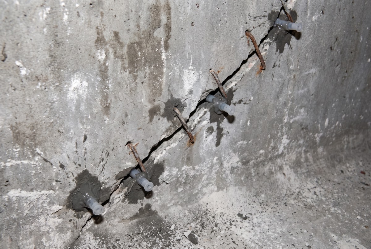 Structural pool crack repaired with steel staples across the crack line in a drained shell